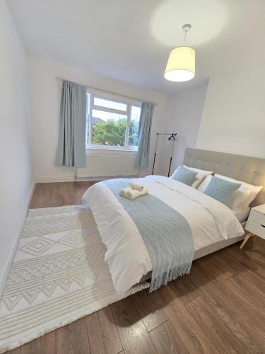 a white bedroom with a large bed and a window at 2bedroom Raynes Park London 30min to Central London Family Friendly in Raynes Park