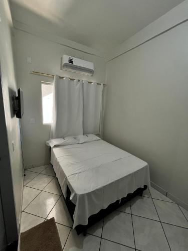 a small white bedroom with a bed and a window at Benni Hotel Marabá in Marabá