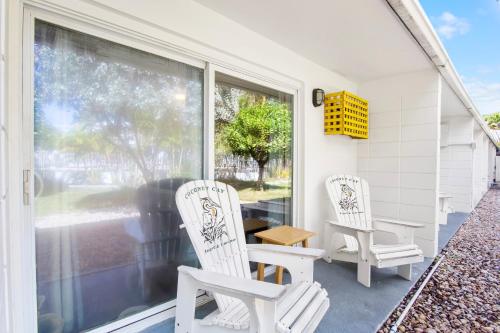 two white chairs sitting on the porch of a house at Coconut Cay Resort in Marathon
