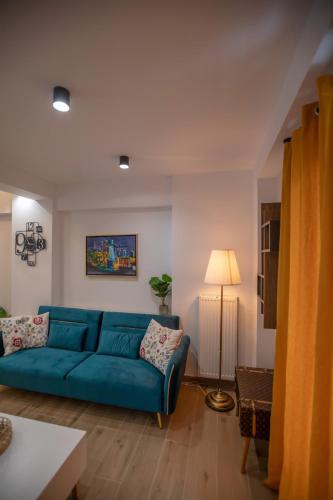 a living room with a blue couch and a lamp at Serenity Karditsa Lofts in Kardítsa