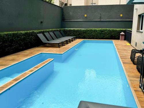 una piscina con 2 tumbonas junto a un edificio en Flat na Liberdade próximo do Metrô, en São Paulo