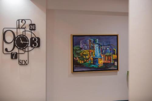 a painting on a wall next to a clock on a wall at Serenity Karditsa Lofts in Kardítsa