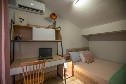 a small room with a desk and a laptop on a bed at Serenity Karditsa Lofts in Kardítsa