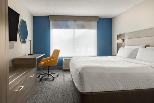 a bedroom with a bed and a desk and a chair at Holiday Inn Express Hotel & Suites Brockville by IHG in Brockville