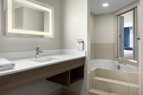 a bathroom with a sink and a tub and a mirror at Holiday Inn Express Hotel & Suites Brockville by IHG in Brockville