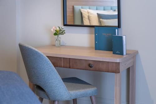 a wooden desk with a mirror and a blue chair at The Ship Hotel in Southend-on-Sea