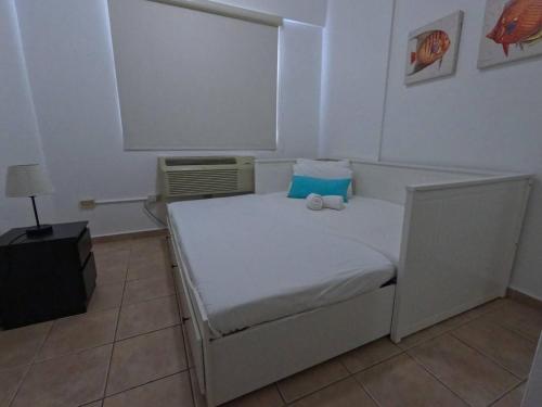 a bedroom with a white bed with a blue pillow at Ocean View, Pool, Gym, Basketball Court, Wifi in Cabo Rojo