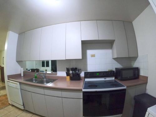 a kitchen with white cabinets and a stove top oven at Ocean View, Pool, Gym, Basketball Court, Wifi in Cabo Rojo