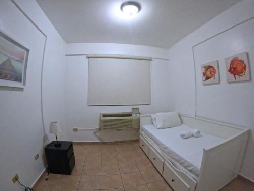 a room with a white bed and a white screen at Ocean View, Pool, Gym, Basketball Court, Wifi in Cabo Rojo