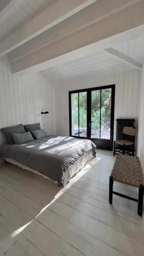 a bedroom with a large bed and a chair at La Cabane du Cap Ferret in Lège-Cap-Ferret