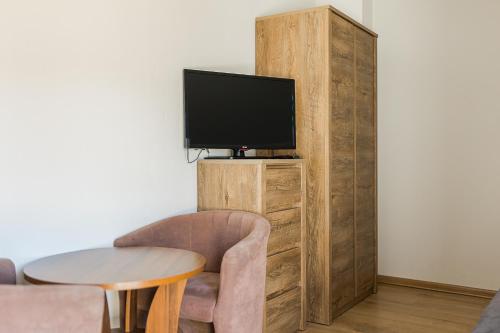 a living room with a tv and a chair and a table at Noclegi Biały Bór Widok na góry i Zalew Soliński 530-487-636 in Polańczyk
