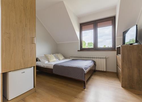 a small bedroom with a bed and a television at Noclegi Biały Bór Widok na góry i Zalew Soliński 530-487-636 in Polańczyk