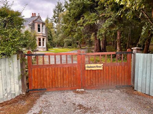 a wooden gate with a sign on it in front of a house at Clashmore House in Dornoch