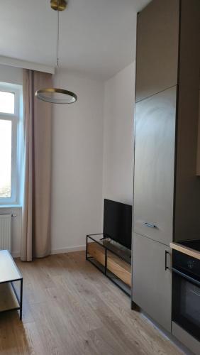 a living room with a television and a refrigerator at Apartament przy parku in Słupsk