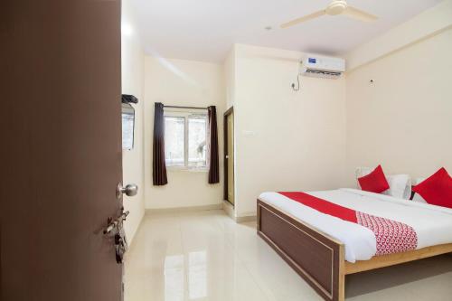 a bedroom with a bed with red pillows and a door at Hotel O Shannu Residency in Secunderabad