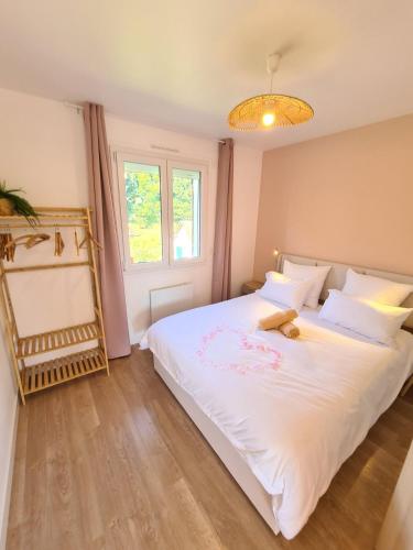 a bedroom with a large white bed with a teddy bear on it at La maison du canal - garage, balcon et jardin in Tonnerre