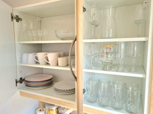 a cupboard filled with glasses and plates and dishes at La maison du canal - garage, balcon et jardin in Tonnerre