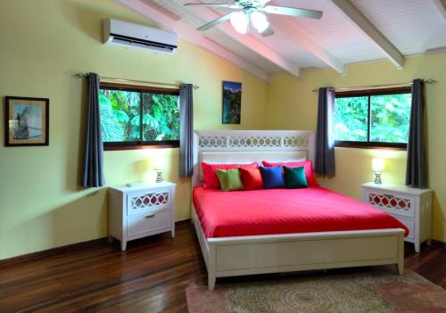 a bedroom with a red bed and two windows at Lovely Tropical Ensuite Bedroom - Pool AC Hot Water in Herradura