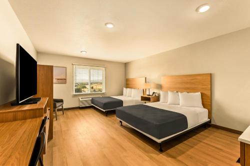 a hotel room with two beds and a flat screen tv at LivAway Suites Salt Lake City- Draper in Draper