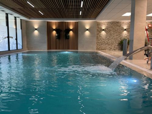 a swimming pool with a fountain in a building at Hotel Červenohorské sedlo in Loučná nad Desnou