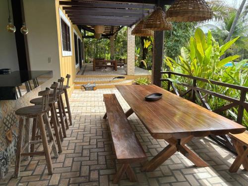 une table et des chaises en bois sur une terrasse dans l'établissement Holiday Villa Praia da Pipa-5 Suites,Areá Gourmet by PipaCharme, à Pipa
