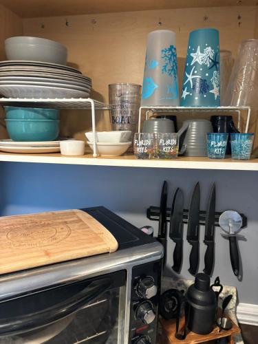 a kitchen with a shelf with plates and utensils at Baycation Houseboat in Tavernier