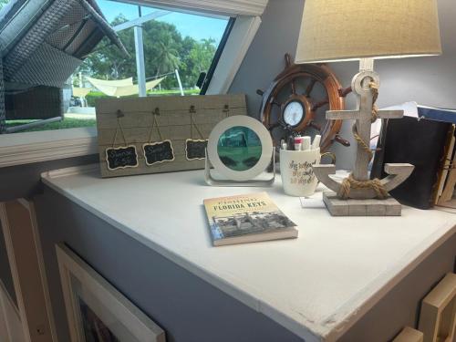 a table with a lamp and a clock and a book at Baycation Houseboat in Tavernier