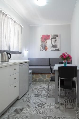 a white kitchen with a table and a couch at Byron Apartments in Tigaki