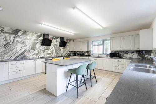 a kitchen with white cabinets and a island with bar stools at Contractor Stay and Holiday Let - Sleeps 2 in Coventry