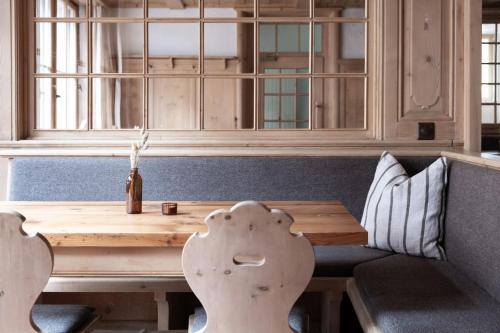 a wooden table and bench in a room with a window at Hotel ÜJA Scuol in Scuol