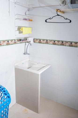 a white bathroom with a sink and a blue chair at El susurro del agua casa blanca exclusiva natural in Ibagué