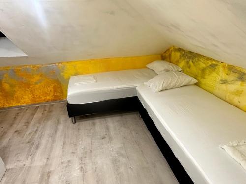 two beds in a small room with yellow walls at Мансарда in Nesebar