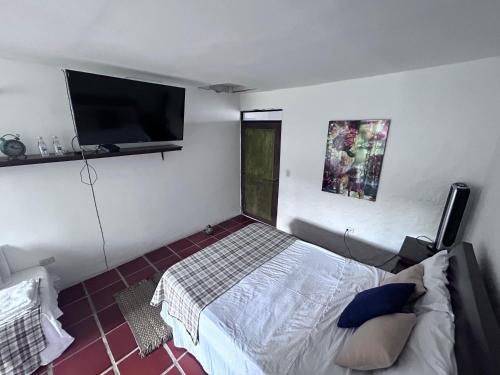 a bedroom with a bed and a flat screen tv at La casona de la loma Ibague in Ibagué