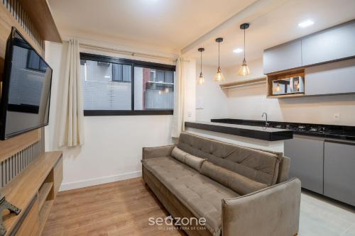 a living room with a couch and a kitchen at Prédio c/ Aptos Novos a 300m da Praia - EEP in Guarapari