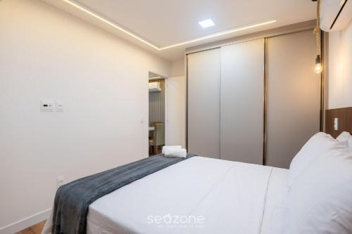 a bedroom with a white bed and a closet at Prédio c/ Aptos Novos a 300m da Praia - EEP in Guarapari