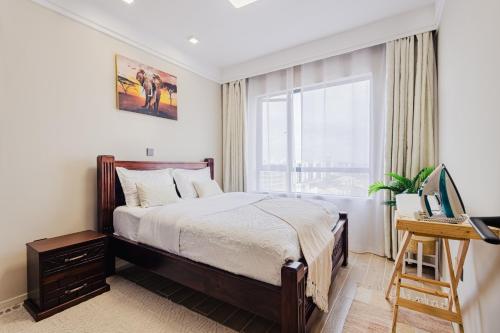 a bedroom with a bed and a desk and a window at Ultimate Safari Retreat,9min to Nairobi JKIA with Pool,Gym,WiFi and Binocular views in Nairobi