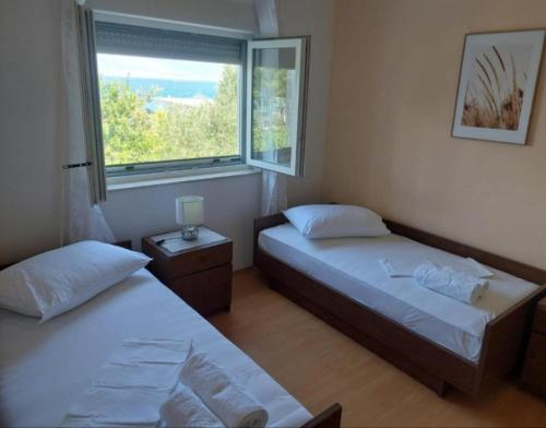two beds in a room with a window at Apartman Silvija Čiovo in Slatine