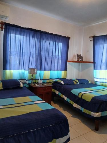 Dos camas en una habitación con cortinas azules. en Casa Laura, en El Venadillo