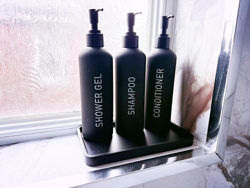 two black bottles sitting on a shelf in a window at The Serene Stays - 3 Bed Home in Oldham Manchester in Oldham