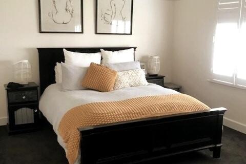 1 dormitorio con cama blanca y negra con almohadas en Kyabram Happy House WIFI Pet Friendly, en Kyabram