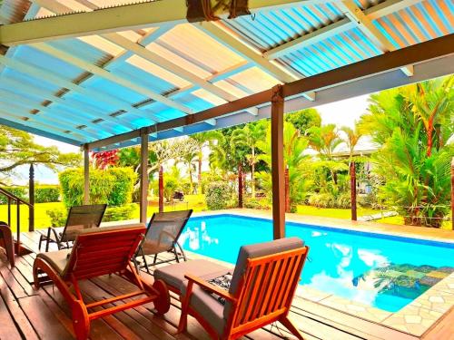 a deck with chairs and a swimming pool at Ocean Breeze Villa in Savusavu
