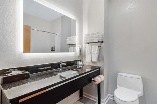 a bathroom with a sink and a toilet and a mirror at Best Western Commerce Inn in Commerce