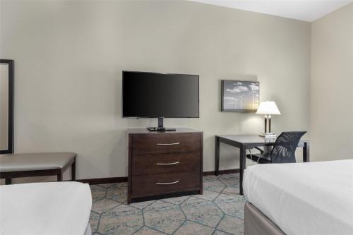 a hotel room with a television and a bed and a desk at Best Western Plus McPherson in McPherson
