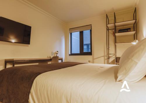 a bedroom with a large bed with a tv on the wall at Almasur Express Punta Arenas in Punta Arenas