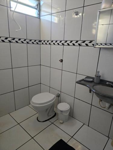 a white bathroom with a toilet and a sink at Casa Sítio in Rio Verde