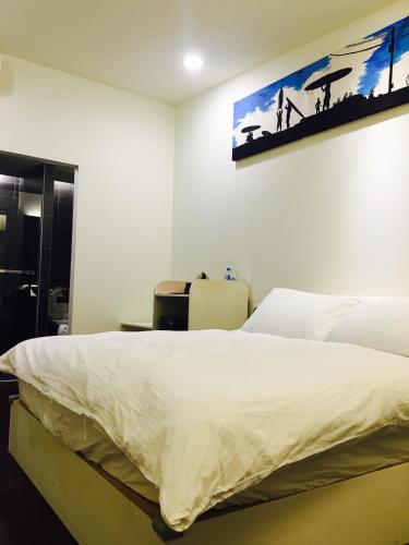 a bedroom with a bed and a painting on the wall at Kenting A&S in Hengchun