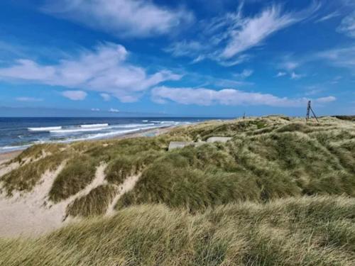 a person walking on a beach near the ocean at 6 person holiday home in Thisted-By Traum in Torsted
