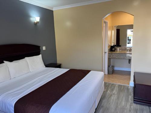 a bedroom with a large bed and a bathroom at Carlton Motor Lodge in Los Angeles