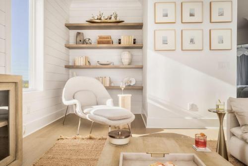 a living room with a white chair and a table at Whitecap - Beachfront Gem with Pool & Elevator in Orange Beach