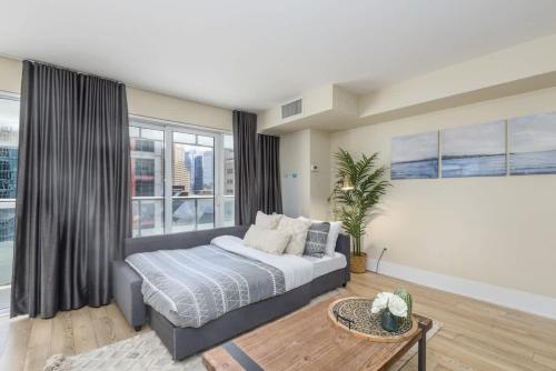 a bedroom with a bed and a large window at Modern 1BR Condo w Patio in Vibrant Front Street in Toronto